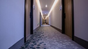 A hotel hallway with carpeted floors, doors on both sides, and overhead lighting. - Greentree Inn Tangshan Caofeidian District Nanbao Development Zone (Tangshan)