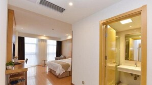 Une chambre d’hôtel comprenant un lit, une table de chevet et une salle de bain avec un lavabo et un miroir.