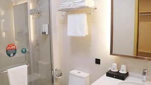 Een moderne badkamer met een glazen douchecabine, een toilet, een wastafel met spiegel en een handdoekhouder.