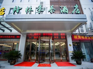 A hotel entrance with a glass door, a red carpet, and potted plants. - Greentree Inn Wuxi Rongchuang Cultural Tourism City Nanquan Town Business Hotel (Wuxi)