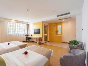 Une chambre d’hôtel avec deux lits, un bureau, une télévision et un petit coin salon.