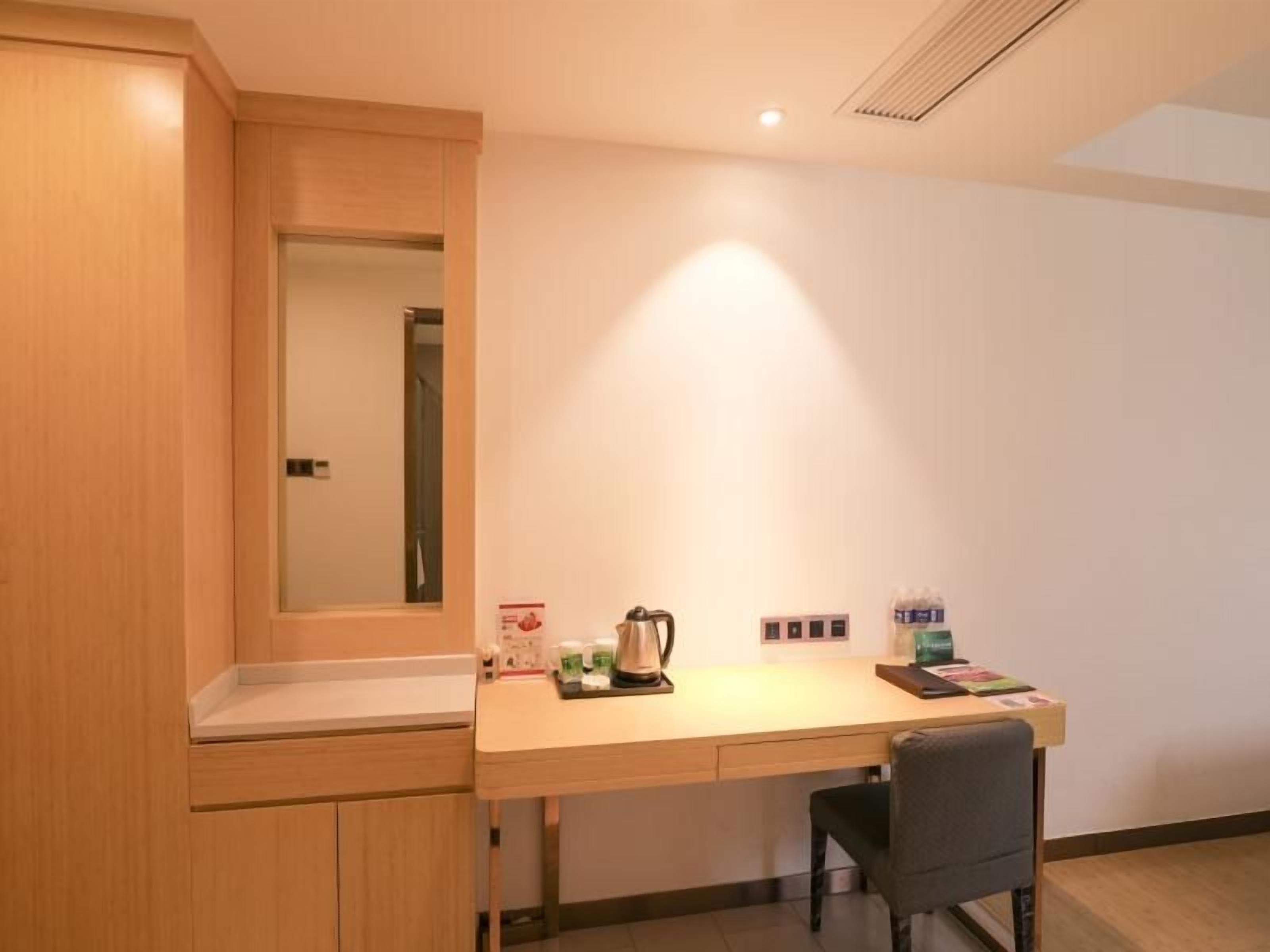 A small, well-lit room with a wooden desk, a chair, and a mirror.
