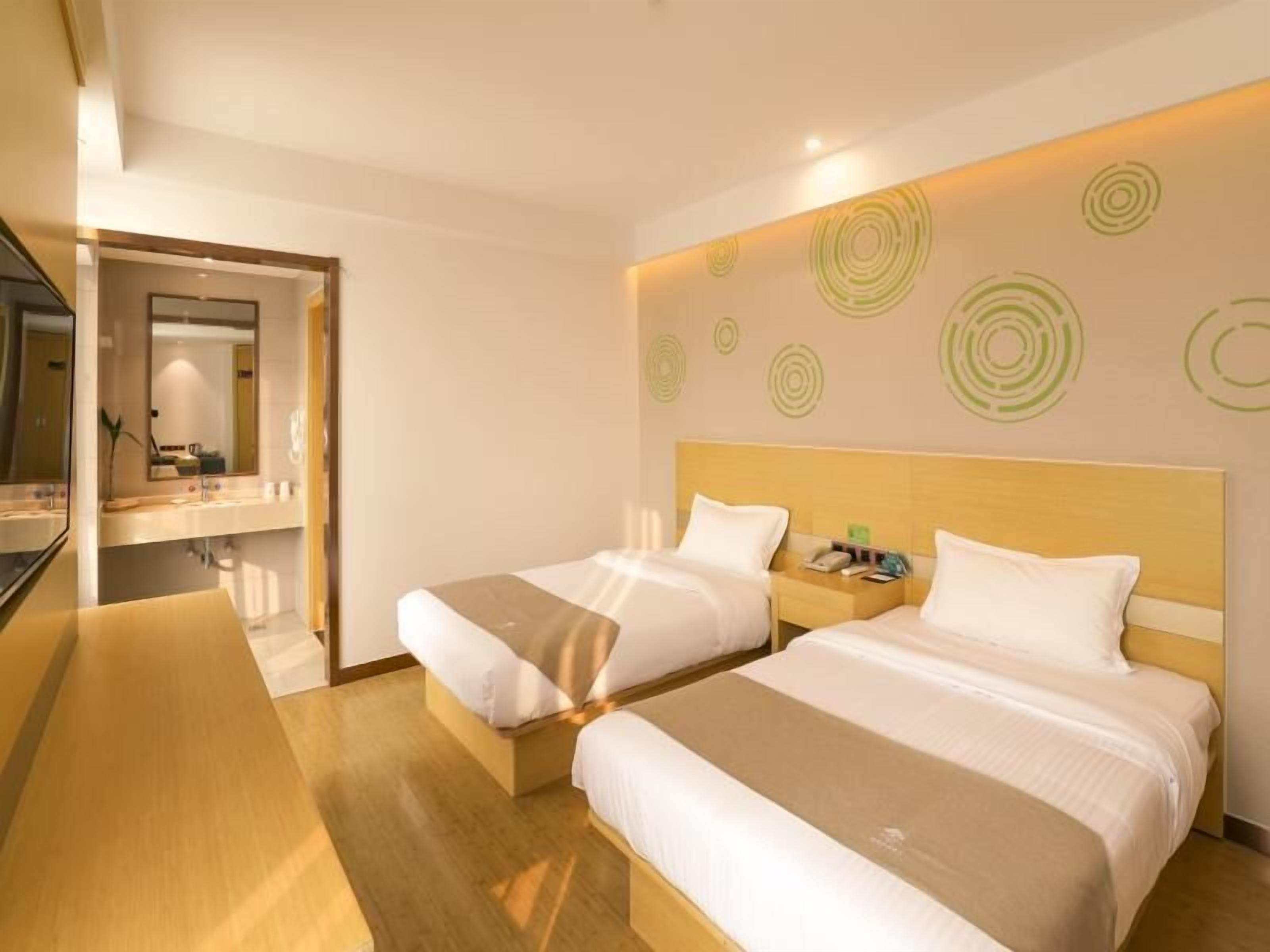 A hotel room with two beds, a wooden headboard, a large mirror, and a wall with circular patterns.