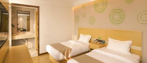 A hotel room with two beds, a wooden headboard, a large mirror, and a wall with circular patterns.
