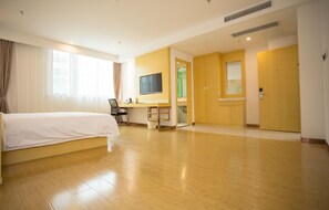 Een hotelkamer met een bed, een bureau, een televisie en een badkamer, zichtbaar door een geopende deur.