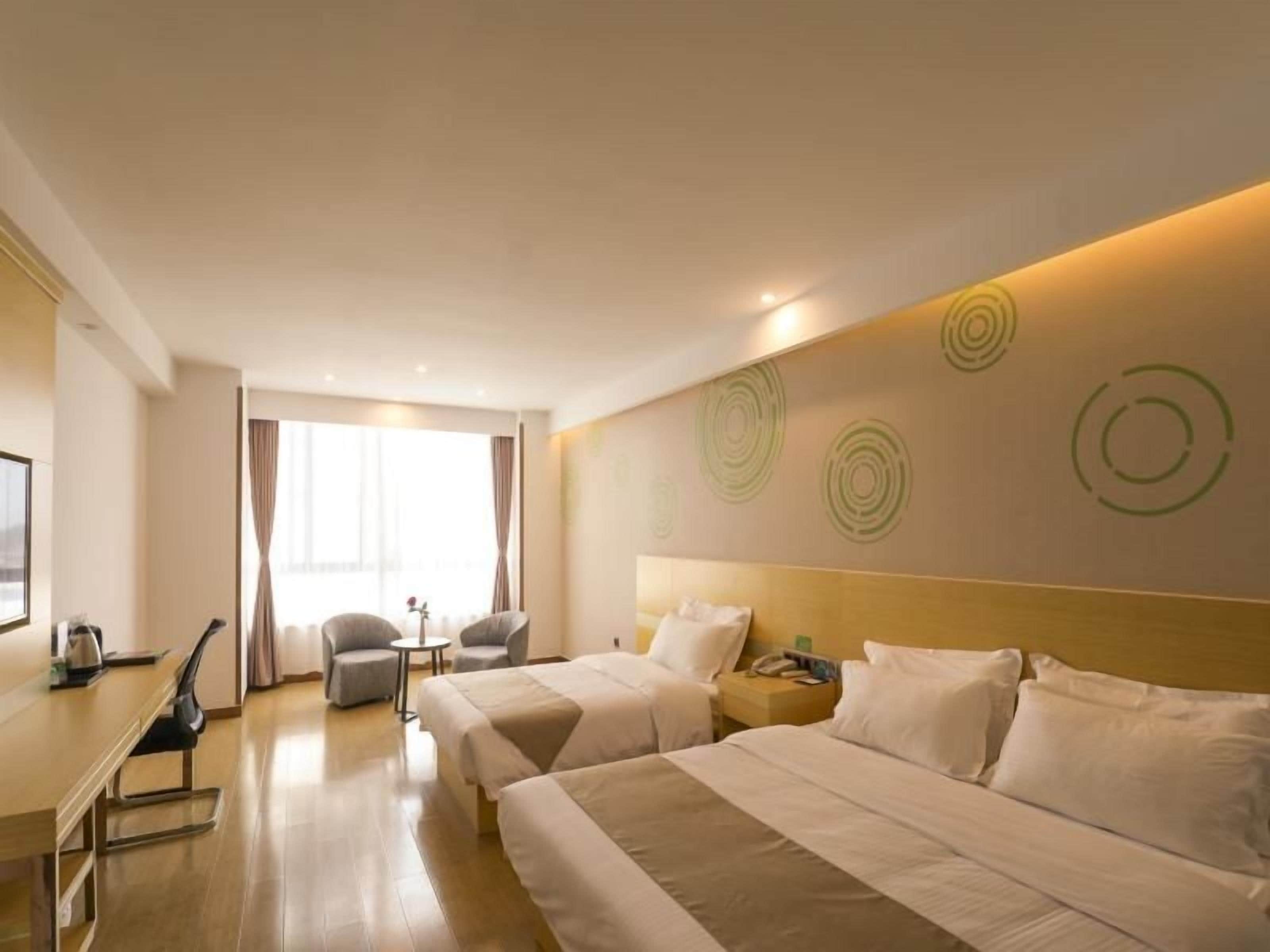 Une chambre d’hôtel avec deux lits, un bureau, une chaise et une petite table.