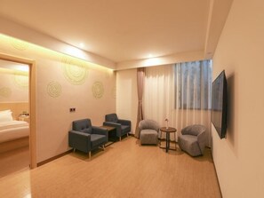 A hotel room with a bed, two armchairs, a small table, and a TV. - Greentree Inn Wuxi Rongchuang Cultural Tourism City Nanquan Town Business Hotel (Wuxi)
