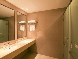 Une salle de bain moderne avec deux lavabos, un grand miroir et un espace douche.