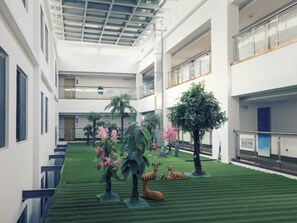 A spacious atrium with a green carpet, artificial trees, and deer sculptures. - Greentree Inn Wuxi Rongchuang Cultural Tourism City Nanquan Town Business Hotel (Wuxi)