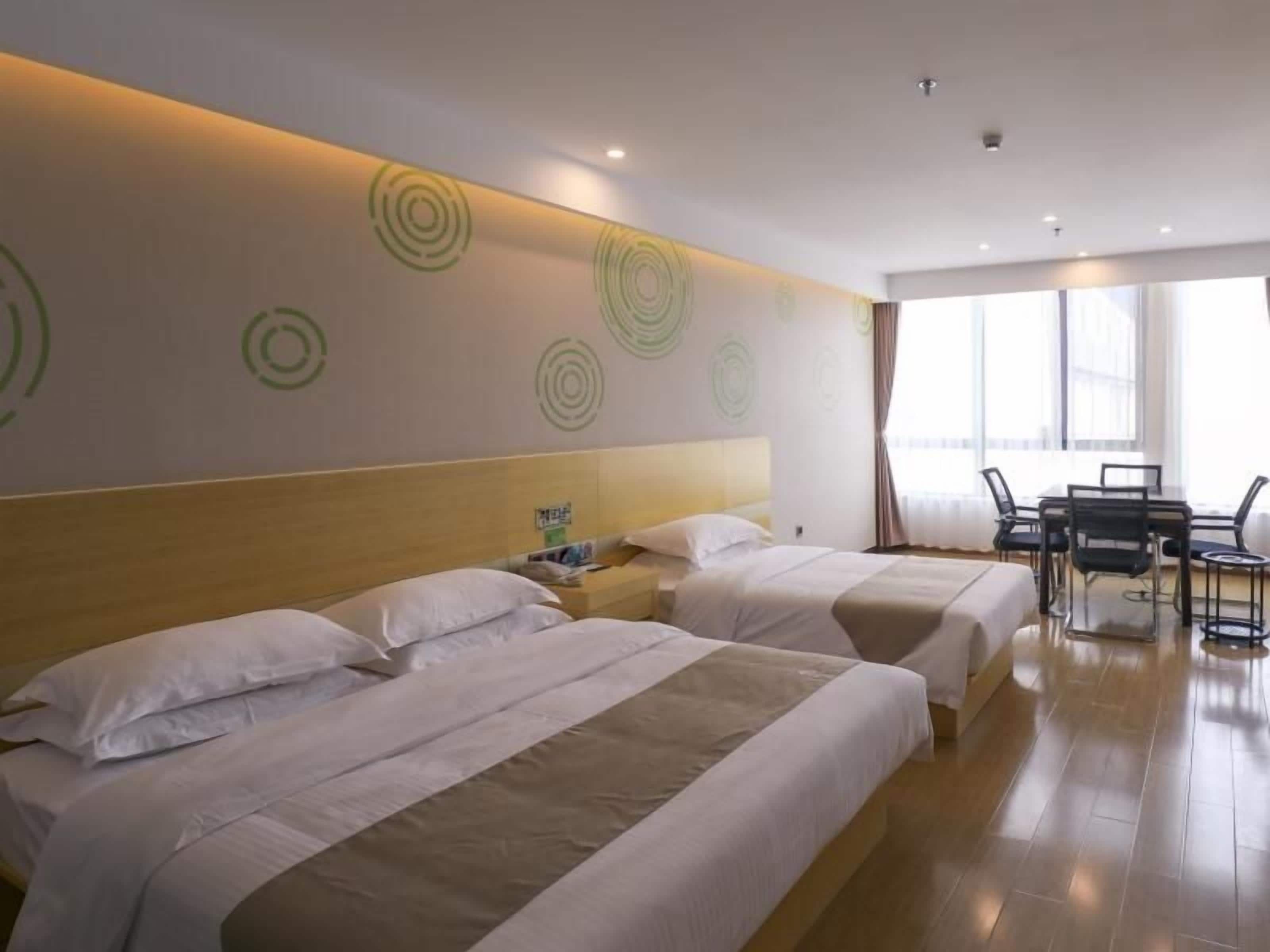 Quarto de hotel com duas camas, uma mesa de jantar e uma janela grande.
