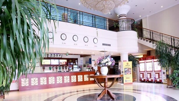 A hotel lobby with a reception desk, a circular marble floor, and a staircase leading to an upper level. - Greentree Inn Rizhao Yantai Road (Rizhao)
