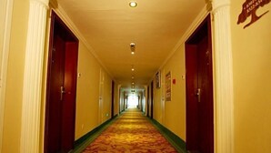 A hotel hallway with a carpeted floor, white columns, and red doors. - Greentree Inn Rizhao Yantai Road (Rizhao)