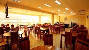 A spacious dining area with multiple wooden tables and chairs, arranged in rows. - Greentree Inn Rizhao Yantai Road (Rizhao)