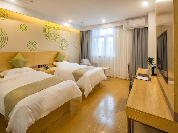Habitación de hotel con dos camas, un escritorio, una silla, una mesita, un espejo y una ventana con cortinas.