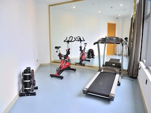 Un gimnasio con equipamiento de ejercicio, incluyendo una cinta de correr, bicicleta estática y pesas.