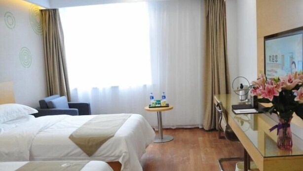 A hotel room with two beds, a desk with a computer, a small table with toiletries, and a window with curtains. - Greentree Inn Anyang Tangyin Changhong Road (Anyang)