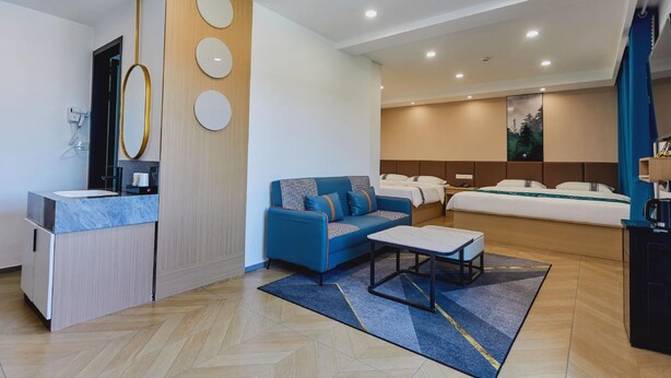A modern hotel room with a sofa, a small table, a bed, and a bathroom with a sink and mirror. - Greentree Inn Shandong Dezhou Qihe County Party Committee Qilu Street Express Hotel (Dezhou)