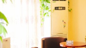 A room with a single brown chair, a small round table, and a wall-mounted air conditioner. - Greentree Inn Shandong Dezhou Qihe County Party Committee Qilu Street Express Hotel (Dezhou)