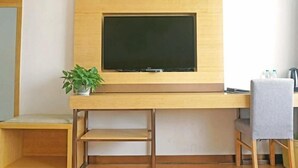 A modern room with a wooden desk, a flat-screen TV, a small plant, and a chair. - Greentree Inn Gongqingcheng City Golf Avenue Peopl (Jiujiang)