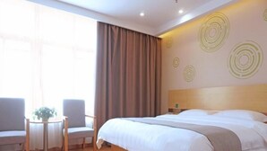 A hotel room with a large bed, two armchairs, a small table with a plant, and a window with curtains. - Greentree Inn Gongqingcheng City Golf Avenue Peopl (Jiujiang)