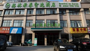A hotel with a green and white sign, multiple windows, and parked cars in front. - Greentree Inn Gongqingcheng City Golf Avenue Peopl (Jiujiang)