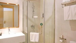A bathroom with a glass-enclosed shower, a white sink, and a mirror with a wooden frame. - Greentree Inn Gongqingcheng City Golf Avenue Peopl (Jiujiang)