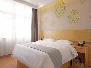 A hotel room with a bed, a nightstand, and a wall with circular patterns. - Greentree Inn Gongqingcheng City Golf Avenue Peopl (Jiujiang)