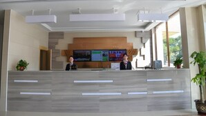 A reception desk with a digital screen, a wooden panel wall, and potted plants. - Greentree Inn Gongqingcheng City Golf Avenue Peopl (Jiujiang)