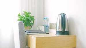 A small wooden desk with a laptop, a kettle, a water bottle, and a potted plant. - Greentree Inn Gongqingcheng City Golf Avenue Peopl (Jiujiang)