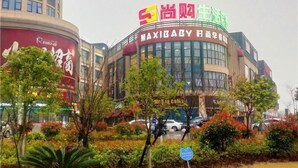 A commercial building with a large sign in multiple languages, surrounded by trees and parked cars. - Greentree Inn Jiaxing Haiyan County Passenger Depo (Jiaxing)