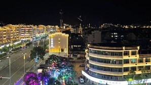 A multi-story hotel with a curved facade, a well-lit street in front, and a tree-lined pathway with colorful lights. - GreenTree Inn Jiangxi Shangrao Wuyuan Bus Station Tang Village Express Hotel (Wuyuan)