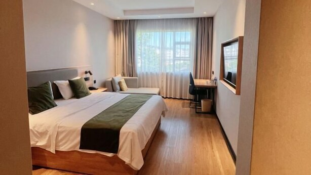A hotel room with a bed, a desk, a chair, and a window with curtains. - GreenTree Inn Jiangxi Shangrao Wuyuan Bus Station Tang Village Express Hotel (Wuyuan)