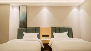 A hotel room with two beds, a nightstand, a painting on the wall, and a ceiling light.