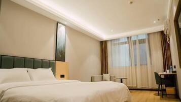 A hotel room with a large bed, a desk, and a chair.