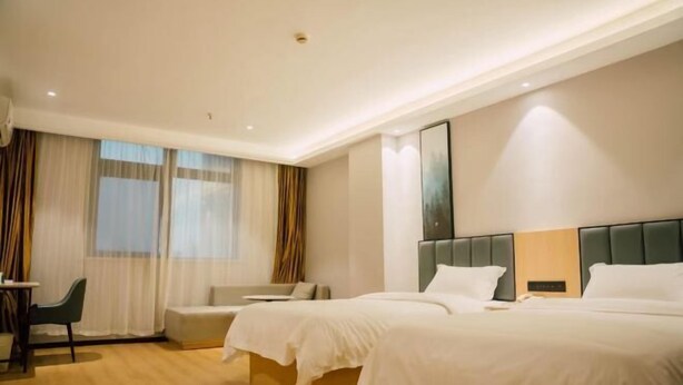 Habitación de hotel con dos camas, un sofá, un escritorio y una ventana con cortinas.