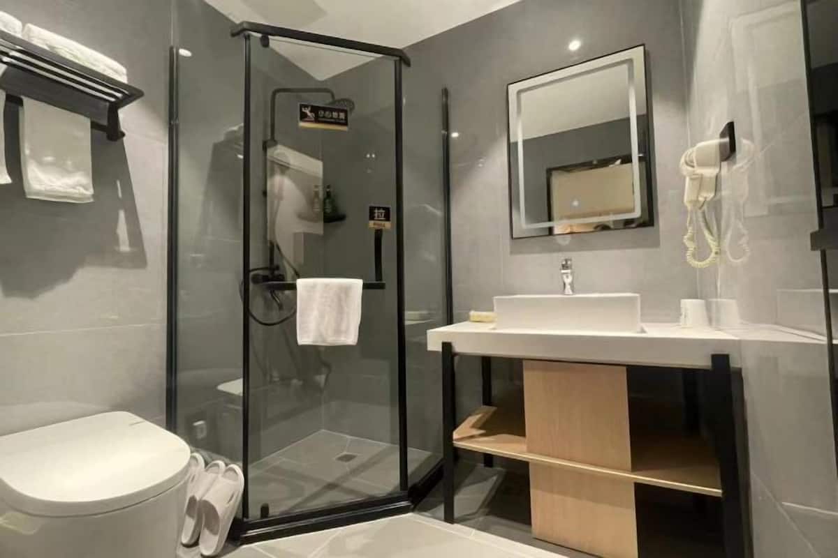 Ein modernes Badezimmer mit einer Duschkabine aus Glas, einem weißen Waschbecken und einem Spiegel darüber.