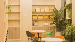 Una habitación con armarios de madera, una estantería con diplomas enmarcados y una mesa redonda con sillas.