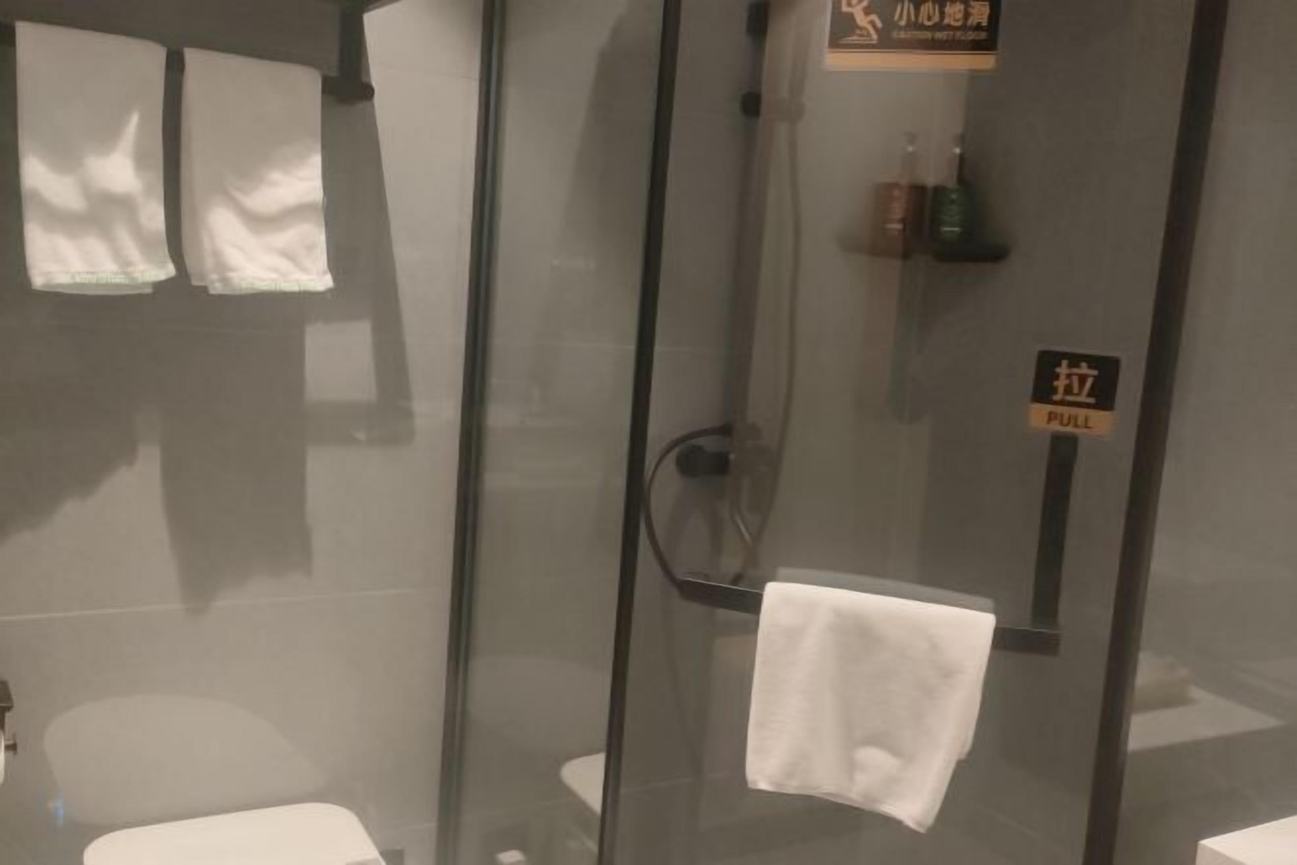 Ein Duschbereich mit Glaswand, ein Handtuch hängt am Türgriff.