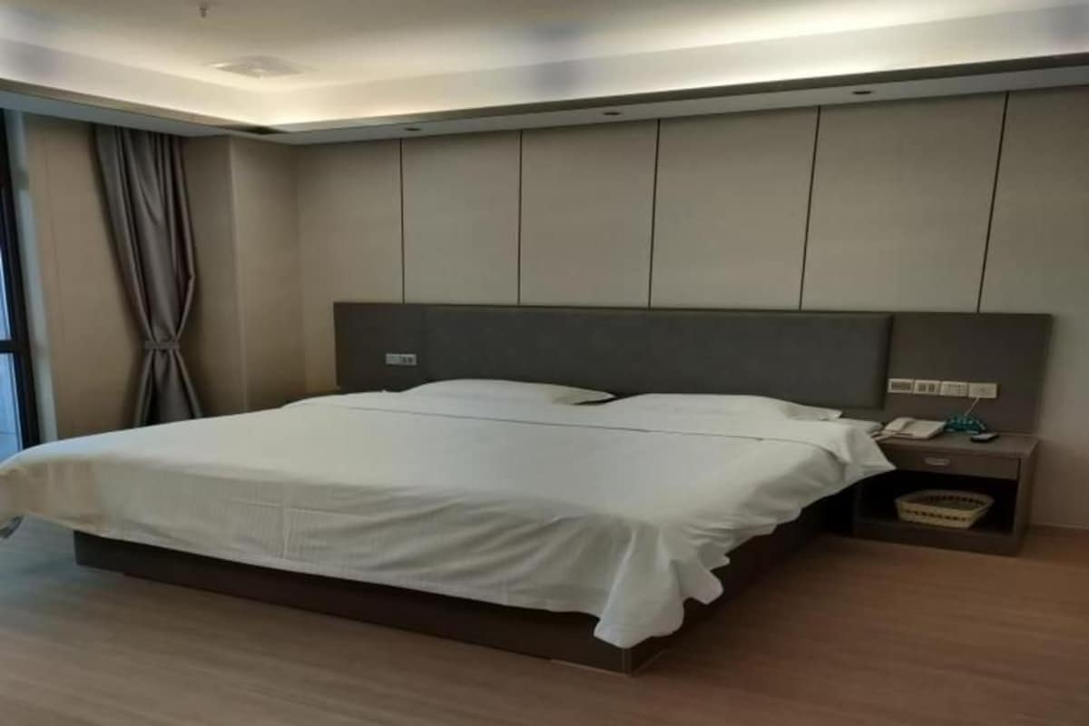 Un dormitorio moderno con una cama grande, una mesita de noche con lámpara y vistas al exterior.