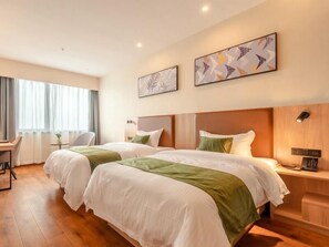 Two single beds with white bedding and green throw pillows, framed artworks above, and a wooden headboard.