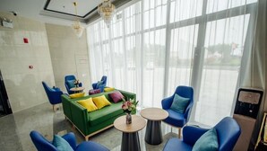 Un espace détente moderne avec un canapé vert, des fauteuils bleus et une table basse.