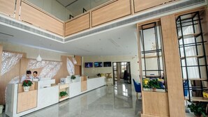Un espace d’accueil moderne avec un comptoir en verre, un lambris en bois et une grande fenêtre.