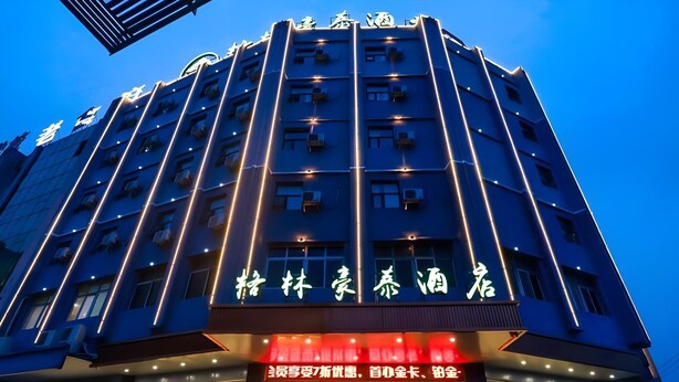 A hotel with a modern facade, illuminated signage, and a revolving door entrance. - Greentree Inn Yichun Development Zone Bus Terminal (Yichun)