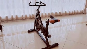 A stationary bike in a room with a tiled floor and sheer curtains. - Greentree Inn Yichun Development Zone Bus Terminal (Yichun)