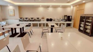 A modern dining area with white tables and chairs, a counter with kitchen appliances, and a refrigerator on the right. - Greentree Inn Yichun Development Zone Bus Terminal (Yichun)