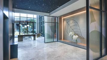 A modern lobby with a starry ceiling, a large leaf artwork, and a seating area with a bench and chairs.