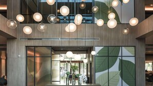 A spacious lobby with a modern design, featuring a central seating area with a sofa and two armchairs, a large window with a view, and multiple hanging spherical light fixtures. - Hyatt Place Beijing Shiyuan (Yanqing)