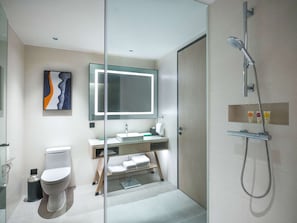 A modern bathroom with a glass partition, a toilet, a sink with a mirror, and a shower.