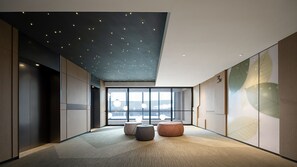 A modern interior with a high ceiling, recessed lighting, large windows, and minimalist furniture.