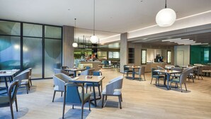 A modern restaurant with wooden flooring, multiple dining tables, and chairs. - Hyatt Place Beijing Shiyuan (Yanqing)